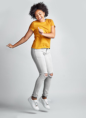 Image showing Jump, excited and young woman celebrating success with smile or motion for freedom and happiness on grey studio background. Energy, winner and jumping for success or joy in the air for achievement