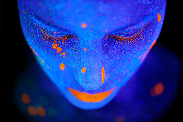 Image showing Creative, face and woman with neon paint in studio for fantasy, art or psychedelic aesthetic. Illusion, creativity and female model with glitter and bright color facial cosmetics by black background.