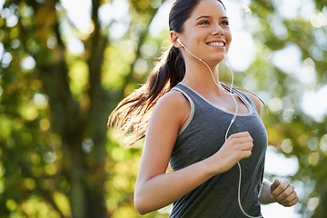 Image showing Fitness, earphones and woman running in a park for health, wellness and outdoor exercise. Nature, sports and female athlete runner doing cardio workout in garden while listening to music and training