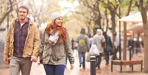 Image showing Happy couple, holding hands and walking in city together in winter for romance or travel outdoors. Man and woman having a walk or stroll in park or town in happiness for romantic trip or traveling