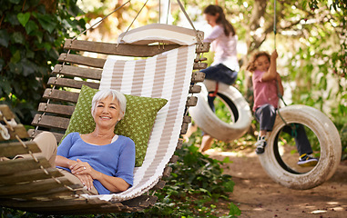 Image showing Relax, happy and senior woman on a hammock while grandchildren play in the garden of the family home. Happiness, smile and portrait of elderly female person in retirement resting outdoor in backyard.