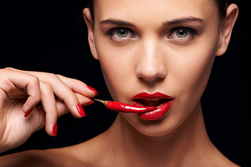 Image showing Beauty, portrait and woman with a chilli in a studio for a sensual, glamour and sexy aesthetic. Cosmetic, makeup and female model with a pepper with red lipstick isolated by a dark black background.