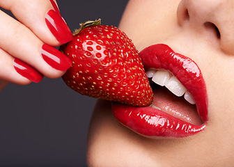 Image showing Beauty, makeup and woman with a strawberry in a studio with red nails and lipstick cosmetics. Health, wellness and closeup of a female model eating fruit for nutrition isolated by a gray background.