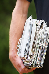 Image showing Closeup, stack and man with newspaper, delivery and daily information with stories, courier and bundle. Zoom, male person and hand with journalism, recycle paper and distribution with sustainability