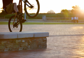 Image showing Closeup, bike and man outdoor, trick and sun flare with training, fun and wellness. Male person, cyclist or biker outside, free style and extreme sports with freedom, professional cycling and parkour