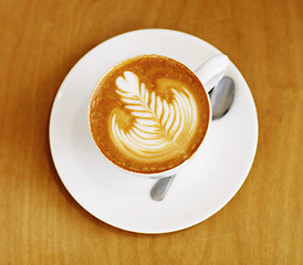 Image showing Latte art, coffee and top view of drink on table in cafe, closeup of hot beverage and artistic design with milk foam. Cappuccino, espresso and creative pattern on caffeine liquid brew in a cup