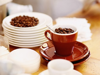 Image showing Cup, roasted coffee beans and cafe industry or shop with quality product for marketing or catering. Texture, abstract or background with brown grain as drink, espresso or caffeine ingredient on table