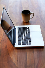 Image showing Remote work with a coffee and laptop on a desk for blogging or social media browsing at a modern restaurant. Computer, freelance and research with wireless technology on a wooden surface from above