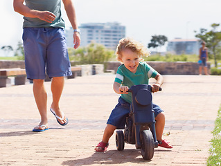 Image showing Happy, toy and motorbike with child and father playing in park for bonding, laugh and fun. Smile, happiness and energy with man and young boy riding on scooter for playful, youth and summer