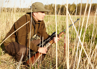 Image showing Hiding, game hunter and gun of man in nature on a safari for shooting and animal spotting. Sun, outdoor and sniper with scope and male person with a hunting weapon in Africa with patience and crouch