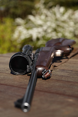 Image showing Hunting, rifle and weapon with a gun on a table outdoor in nature on a game reserve or blurred background. Sports, scope and sniper with hunter or military equipment on a wooden surface outside