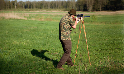 Image showing Hunter, gun and man in field in nature on a Africa safari for animal shooting with a weapon on vacation. Hunting sport, male person and target hunt practice of a traveler in camouflage with a scope