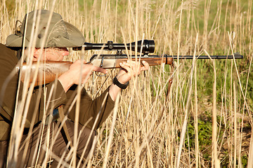 Image showing Nature, wildlife and male hunter with a shotgun while in camouflage shooting in outdoor field. Grass, safari and man hunting animals with rifle weapon hiding in plants to shoot target in countryside.