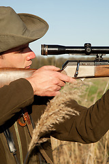 Image showing Hunting, gun and man on a Africa safari in field for shooting animals on wildlife holiday. Weapon, sniper and male person aim for wild game in nature with hunt and scope for target shot in the sun