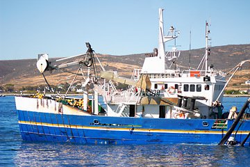 Image showing Fishing boat, ocean and offshore with a commercial and fisherman transportation on water. Ship, harbor and nature with port outdoor by the sea with sailing and calm travel in summer in the sunshine