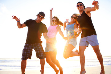 Image showing Friends, jump and beach portrait in sunset with freedom, youth and happiness on vacation together. Excited men, women and smile outdoor by ocean, sunshine and waves in summer, holiday and happy group