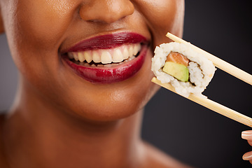 Image showing Mouth, eating and woman with sushi and chopsticks in studio for healthy food or teeth. Black female model with makeup on dark background for wellness glow, diet and seafood or salmon closeup