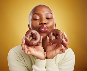 Image showing Sweets, smile and black woman with donuts, funny and happiness with expression, crazy or silly. Female person, dessert or goofy model with facial, chocolate or sugar against a brown studio background