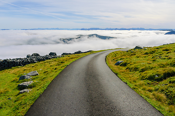 Image showing Mountain peaks poked out of fog on the coast by a road