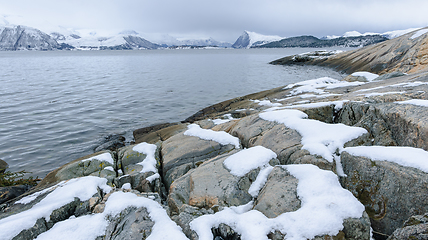 Image showing Snow-covered coastline with mountains on the horizon