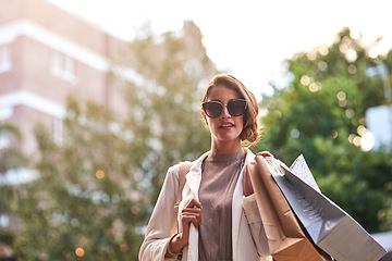 Image showing Portrait, shopping bags or rich woman in city or urban street for boutique retail sale or clothes in sunglasses. Smile, client or fashionable girl customer on city road walking with luxury products