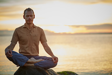 Image showing Go deep and then let it go. Shot of a man sitting in the lotus position during his yoga routine at the beach.