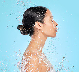 Image showing Skincare, water and profile of woman on blue background for wellness, healthy skin and cleaning in studio. Beauty, shower and female person with splash for facial grooming, washing and body care