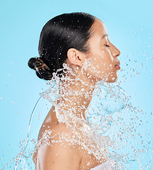 Image showing Beauty, water and face of woman on blue background for wellness, healthy skin and cleaning in studio. Skincare, shower and female person profile with splash for facial grooming, washing and body care