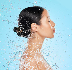 Image showing Beauty, water and face profile of woman on blue background for wellness, healthy skin and cleaning. Bathroom, shower and female person with splash for facial grooming, washing and skincare in studio