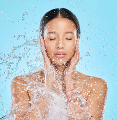 Image showing Skincare, water and face of woman on blue background for wellness, healthy skin and cleaning in studio. Bathroom, shower and female person with splash for facial grooming, washing and body care