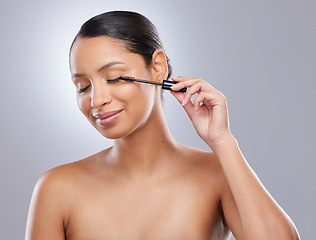 Image showing Brush, mascara and woman in studio for makeup, cosmetics and results on grey background. Eyelash, curling and face of Indian female model with beauty tool for treatment, application or volume