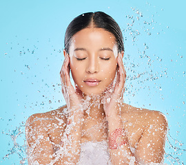 Image showing Skincare, water splash and face of woman in studio for wellness, healthy skin and cleaning. Bathroom, shower and female person with liquid for facial grooming, washing and beauty on blue background