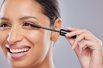 Image showing Makeup, mascara and happy woman with brush in studio for beauty, cosmetics and application on grey background. Eyelash, smile and face of Indian lady model with tool for volume, glamour or aesthetic