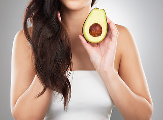 Image showing Hair care, wellness and woman with an avocado in a studio for a natural, organic or health mask. Self care, beauty and closeup of a female model with a fruit for a hair treatment by a gray background