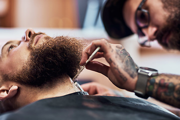 Image showing Dont come between a man and his beard. Cropped shot of a handsome young man getting his beard trimmed and lined up at a barbershop.