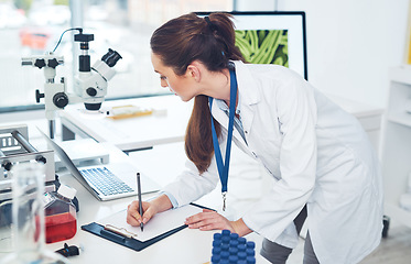 Image showing I have to right down everything I see. Cropped shot of a focused young female scientist making notes in a book while doing tests inside of a laboratory during the day.