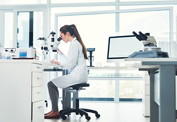 Image showing Paying close attention to detail. Cropped shot of a focused young female scientist looking through a microscope while doing tests inside of a laboratory.