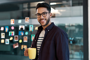 Image showing Caffeine helps me get through the day. Cropped portrait of a handsome young businessman wearing spectacles and standing in his office while drinking a cup of coffee.
