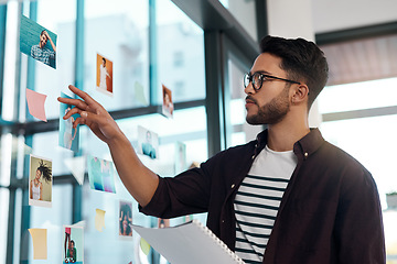 Image showing This is the one I need. Cropped shot of a handsome young businessman standing alone in his office and working with post-its and polaroids.