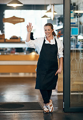 Image showing She makes her cafe feel like home. Shot of a mature woman standing at the entrance of her cafe and waving.