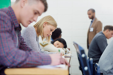 Image showing This lecture hall is completely focused. Shot of a group of university students writing an exam.