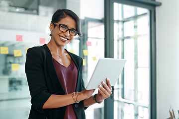 Image showing Its been a busy but successful day. Shot of an attractive young businesswoman standing alone in the office and using a digital tablet.