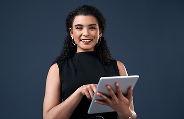 Image showing Staying up to date with social media. Cropped portrait of an attractive young businesswoman standing alone and using a tablet against a gray background in the studio.