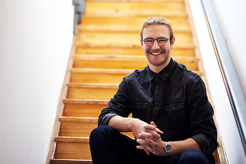 Image showing I am happy with my career choice. Cropped portrait of a handsome young businessman sitting alone on the wooden staircase in his office.