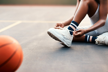 Image showing I dont want to trip of the court. Cropped shot of an unrecognizable sportswoman sitting on the court and tying her shoelaces before playing a game of basketball.