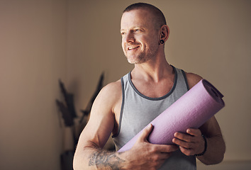 Image showing Yoga helps me slow down and appreciate life. Cropped shot of a handsome young man standing alone and holding his yoga mat before an indoor yoga session.