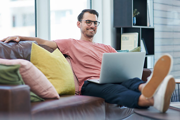 Image showing High website traffic makes a happy entrepreneur. Shot of a young man using a laptop while relaxing on a sofa.