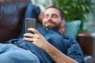 Image showing Nothing says self service like smart apps. Shot of a young man using a smartphone while relaxing on a sofa.