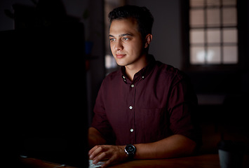 Image showing Wrapping up some deadlines. Shot of a young businessman working on a computer in an office at night.