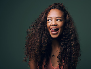 Image showing Natural beauty, tongue out and happy gen z girl with hair, curly and curious on green background. Afro, wellness care and female model with fun, emoji and silly face, personality or comic in studio